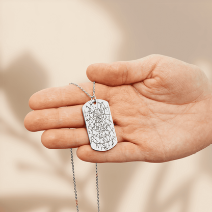Stainless steel star map tag pendant engraved with the night sky of a date and place, held in an open hand
