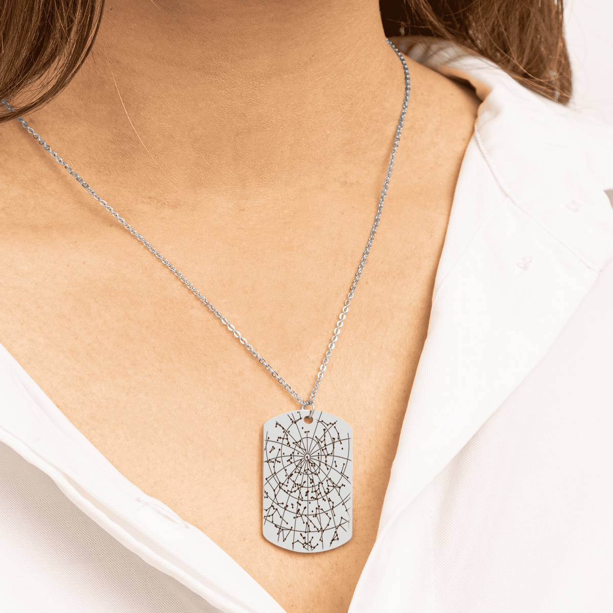 Stainless steel star map tag necklace worn over a white shirt
