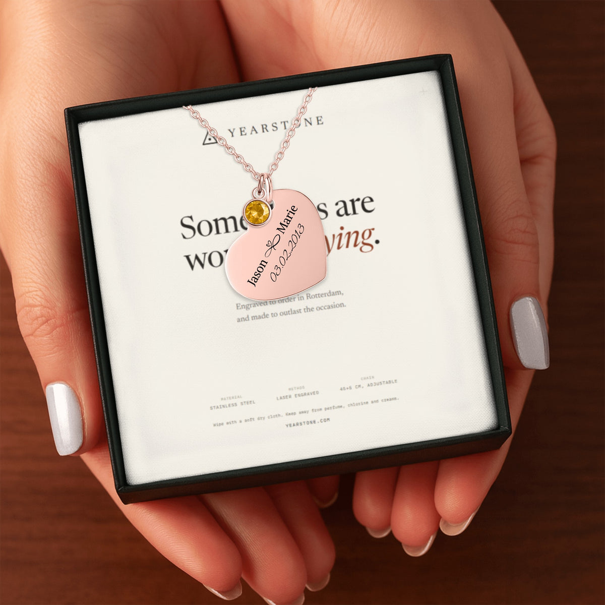 Hands holding the gift box with a rose gold plated engraved heart necklace