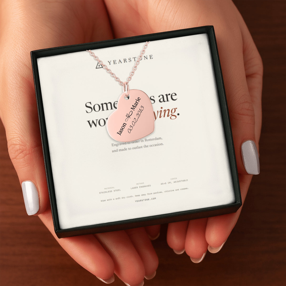 Hands holding the gift box with a rose gold plated engraved heart necklace